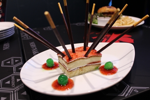 「Food No.14ビーストモード／690円。2号機の獣化第2形態（第1種）な甘いケーキ。食べるときは人間を捨ててかぶりついてください。」リミッターを模したポッキーが大量に刺さったケーキ。見た目のインパクトもさることながら、たっぷりかかったストロベリーソースと、スポンジケーキのマッチングにも注目。
